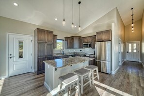 Eine moderne Küche mit Granit Arbeitsplatten, Edelstahlgeräten und Holzschränken.