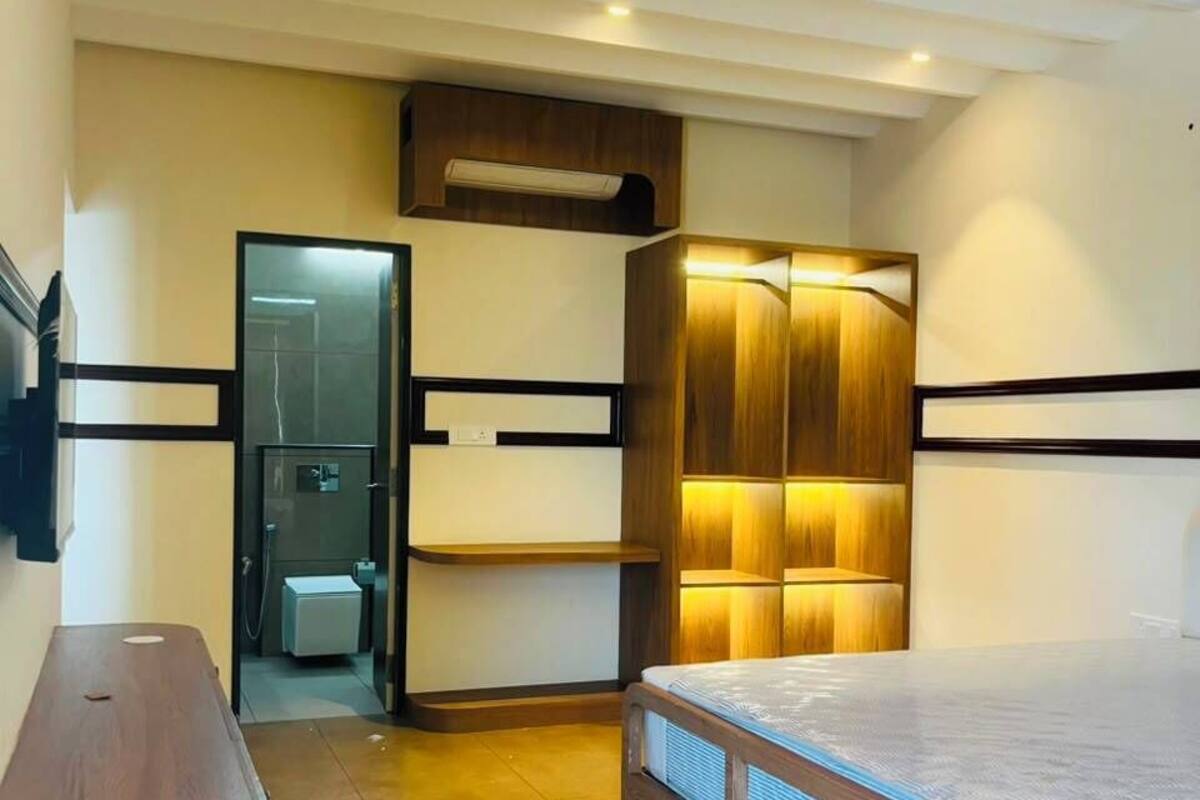 Un dormitorio con cama, un banco de madera, un armario con repisas iluminadas y un ventilador de techo.