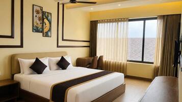 A hotel room with a large bed, a desk, a ceiling fan, and a window with curtains.