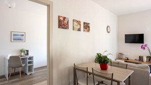 Ein modernes Wohnzimmer mit Essbereich, Fernseher und Kunstwerken an der Wand.