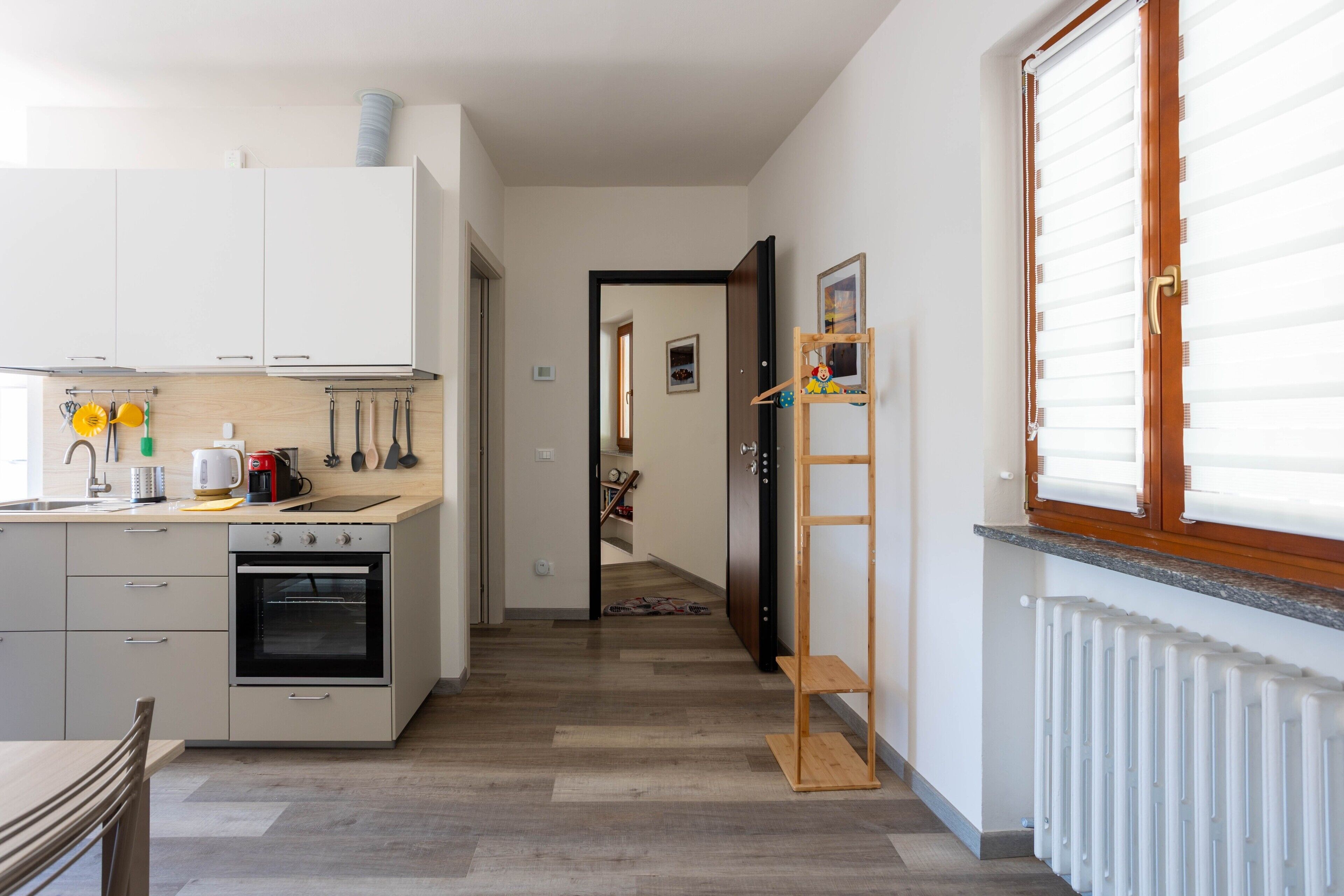 A kitchen with white cabinets, an oven, and a countertop with kitchen utensils.