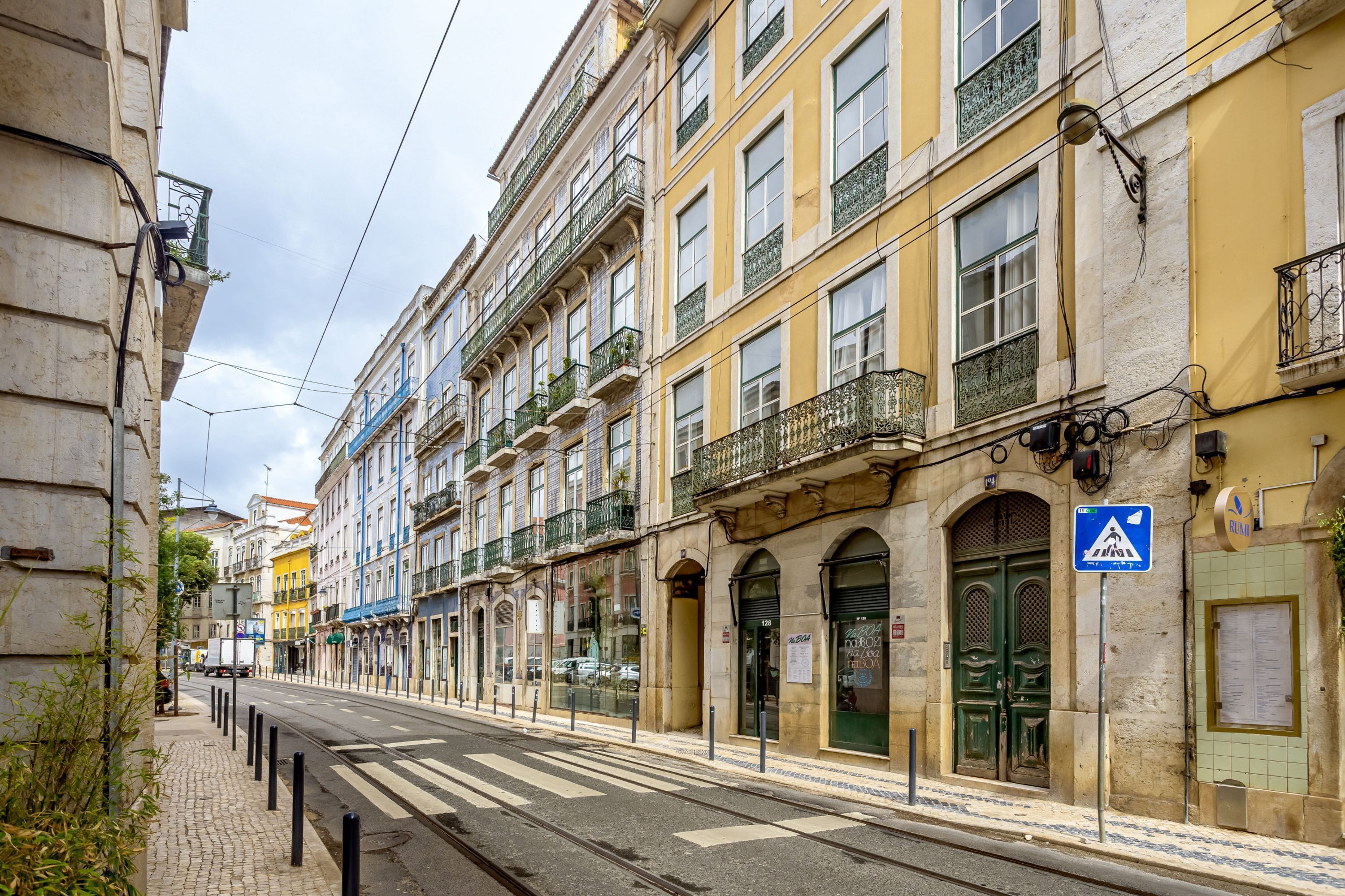 Une rue bordée d’immeubles, avec une ligne de tramway et un passage piéton.
