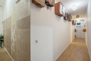 Un pasillo con piso de madera, paredes blancas y un aire acondicionado instalado en la pared.