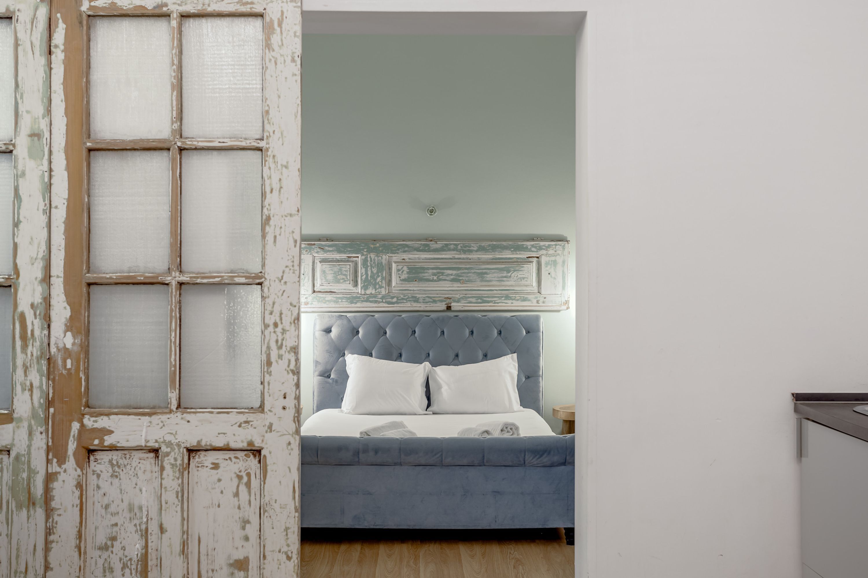 A room with a bed, a door with a frosted glass panel, and a light-colored wall.
