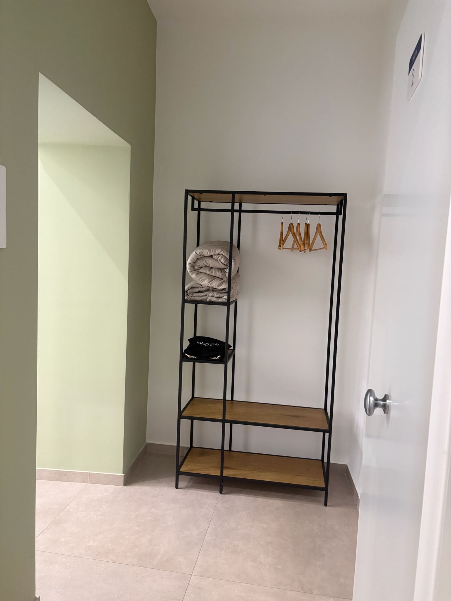 A room with a metal wardrobe, a tiled floor, and a door with a silver handle.