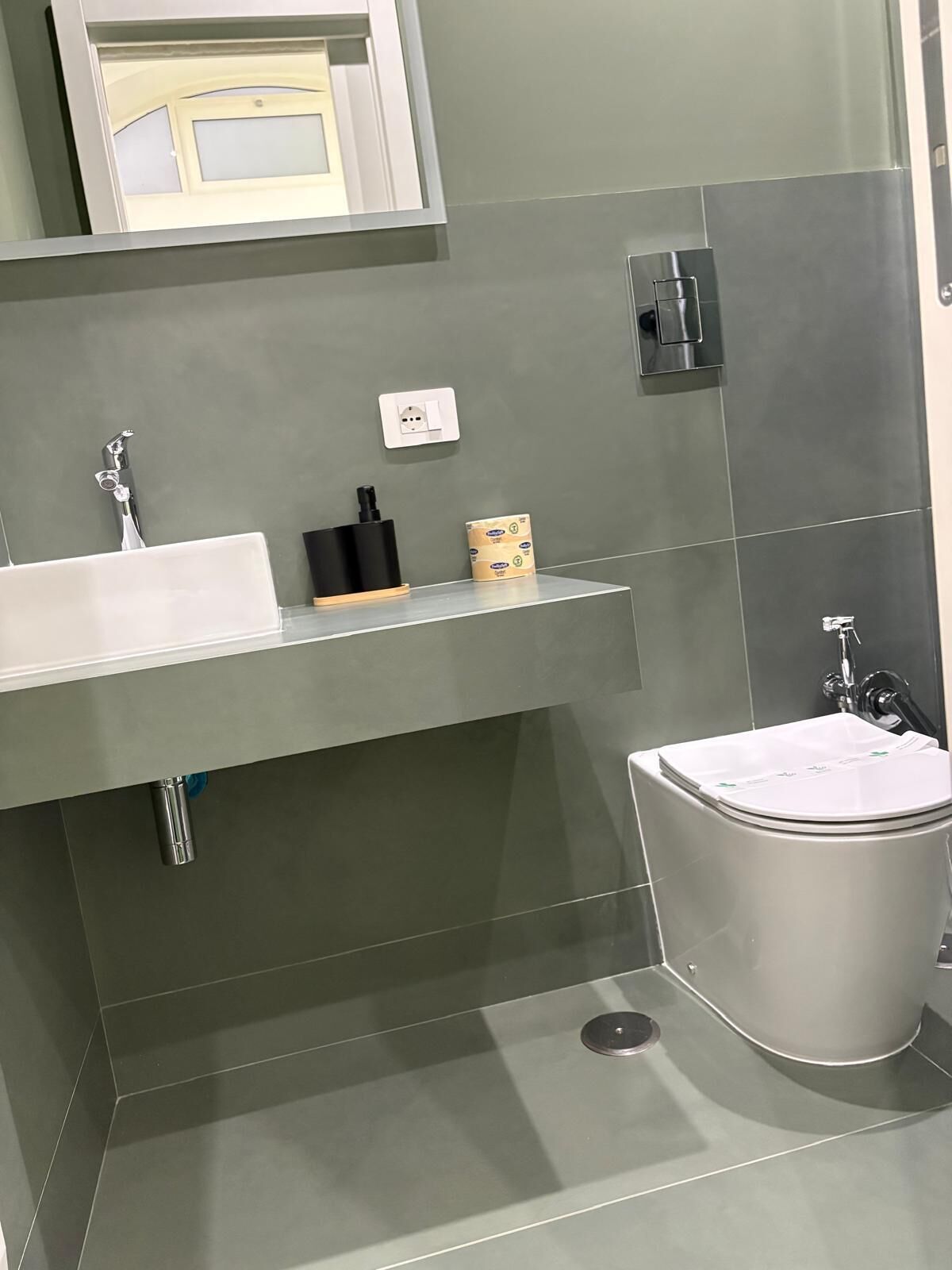 A modern bathroom with a white sink, a toilet, and a mirror.