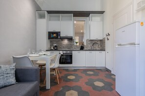 Eine kompakte Küche mit weißen Schränken, einer Mikrowelle, einem Herd und einem Kühlschrank.