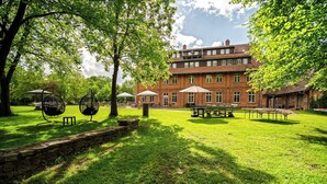 A spacious courtyard with a brick building, outdoor seating, and a stone wall.