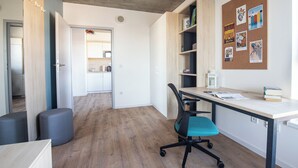 A modern office space with a desk, office chair, and a corkboard with various items pinned to it.