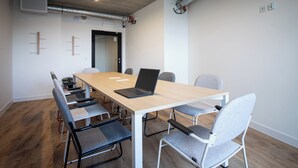 Una sala de conferències amb una taula llarga, sis cadirees i un ordinador portàtil.