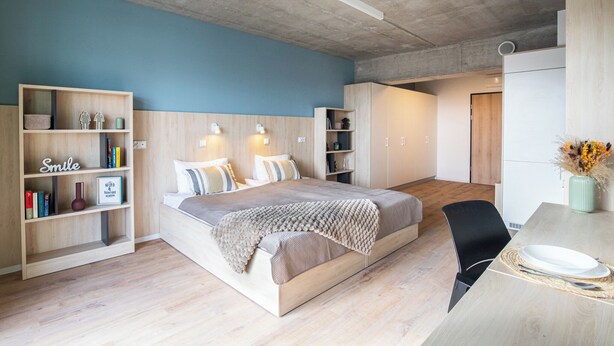 A modern bedroom with a bed, bedside tables, a desk, and built-in shelving.
