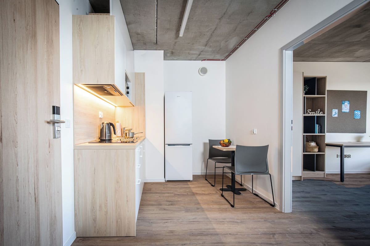 Une cuisine moderne dotée d’une cuisinière intégrée, d’un réfrigérateur blanc et d’un coin repas avec une table et des chaises.