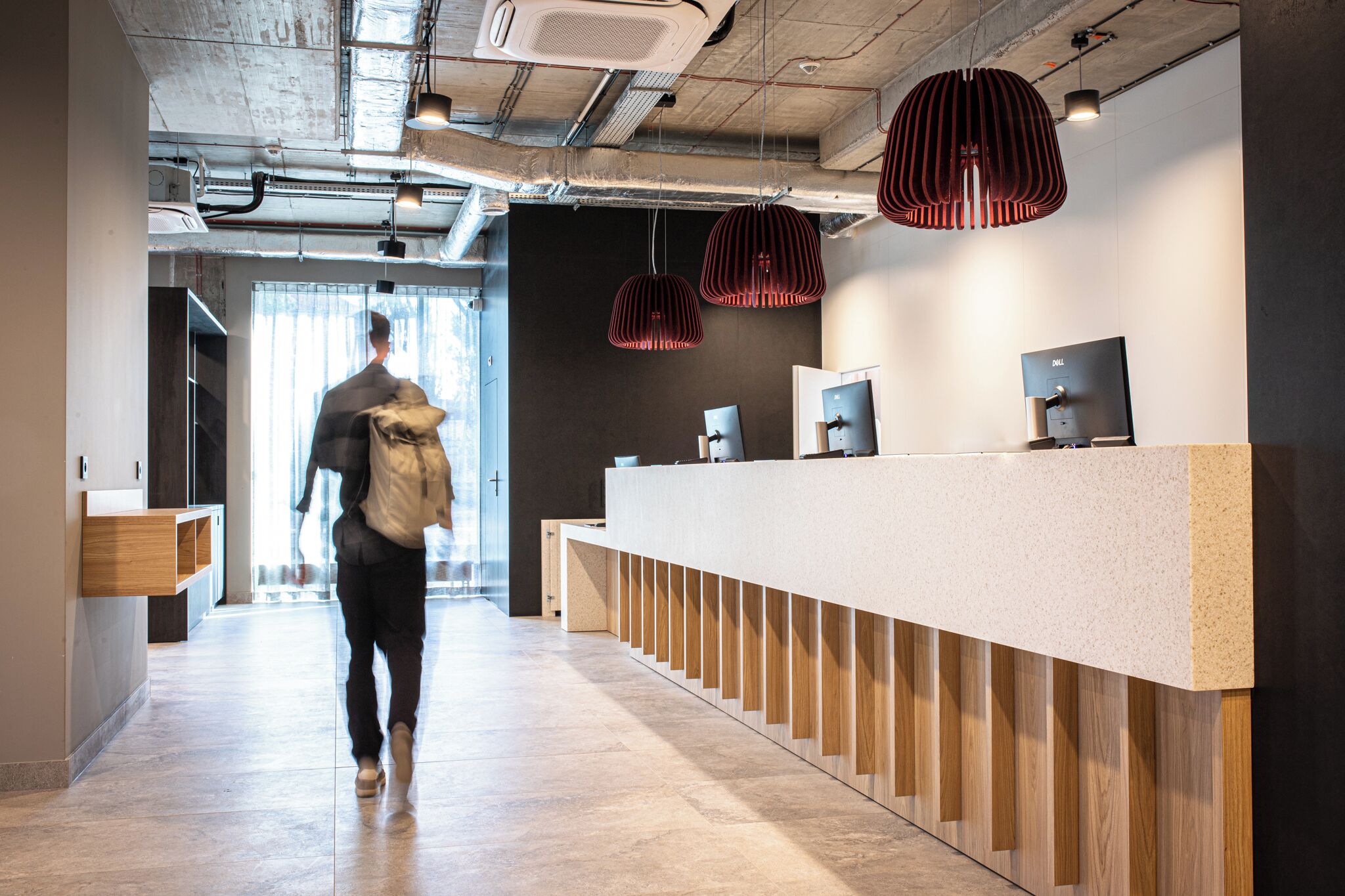 Un área de recepción moderna con una larga barra, paneles de madera e iluminación colgante.