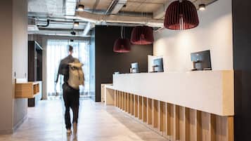 Un área de recepción moderna con una larga barra, paneles de madera e iluminación colgante.