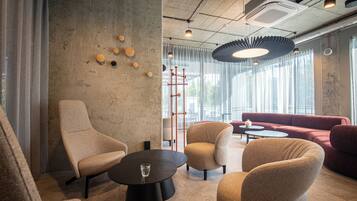 A modern interior with a concrete wall, a red sofa, and a round table with a glass.