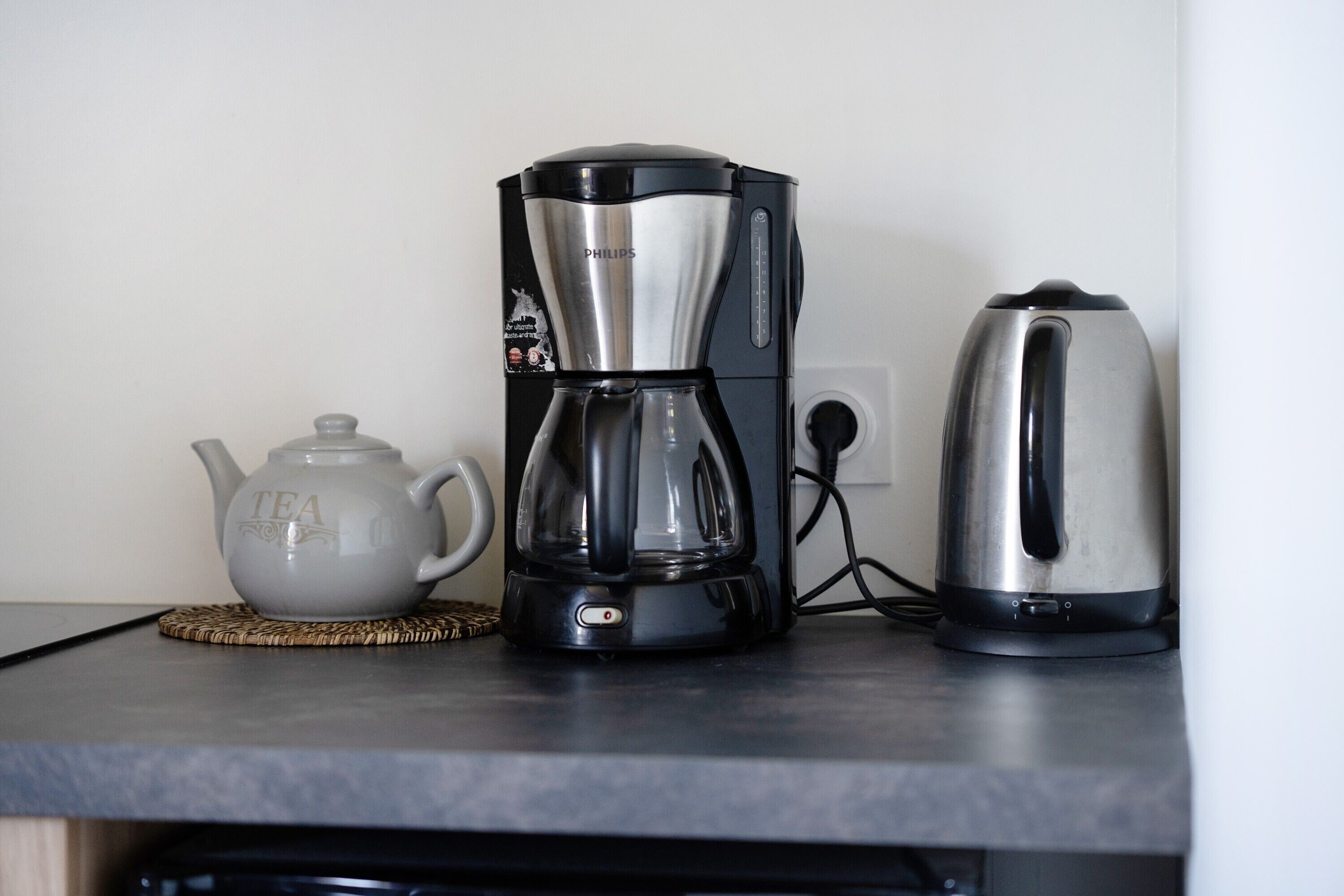 Una cafetera, un bllot i una tetera damunt un taulell de cuina.
