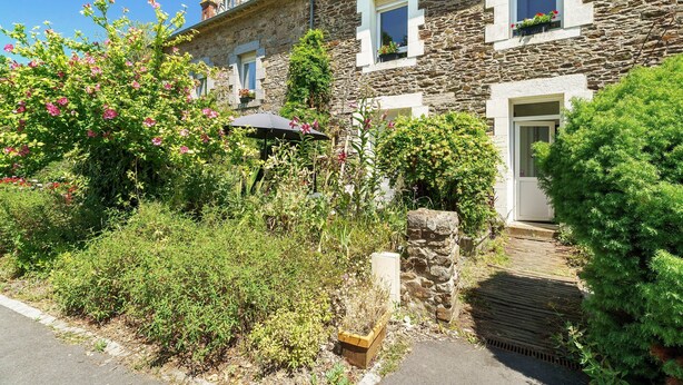 A stone building with a wooden door, a window with a flower box, and a small garden with pink flowers. - Apartment "Aurore" with Wi-Fi in Cancale, 1st Floor (Cancale)
