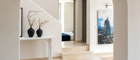 A modern interior with a staircase, a white console table with vases, and a large painting.