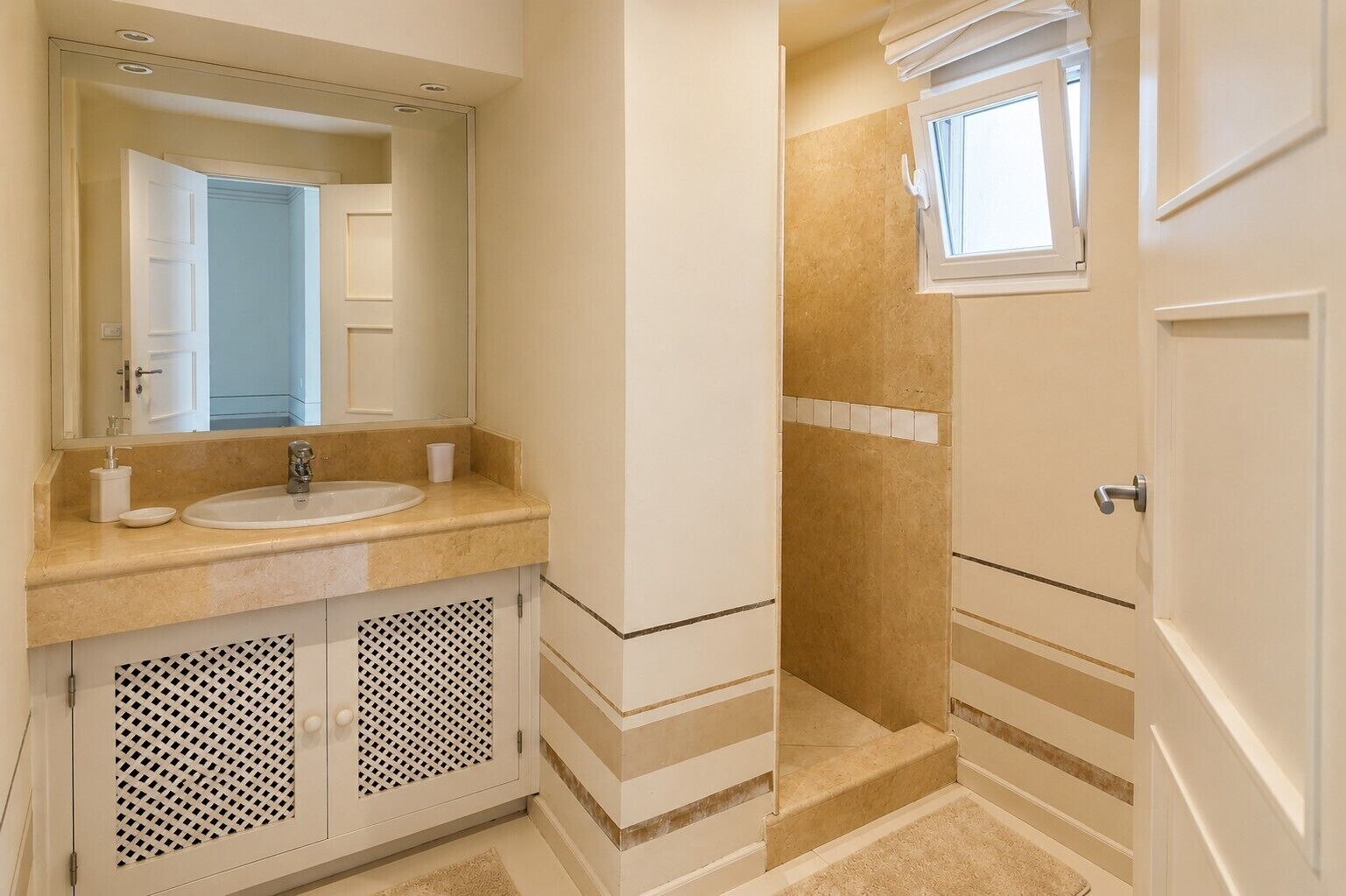 Un baño con lavamanos, espejo y zona de ducha.
