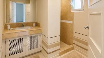 Un baño con lavamanos, espejo y zona de ducha.