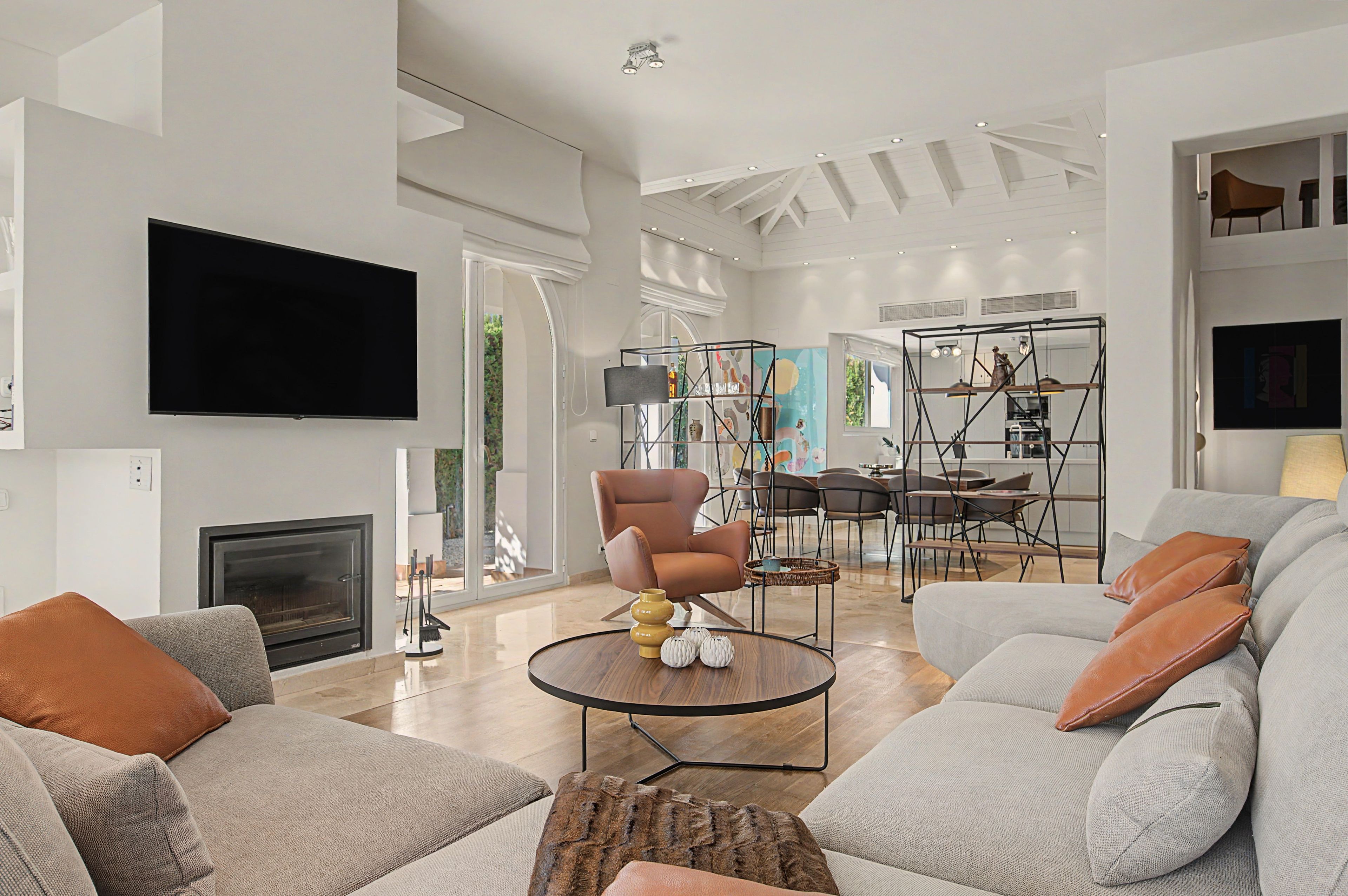 A modern living room with a fireplace, sofas, a coffee table, and a TV mounted on the wall.