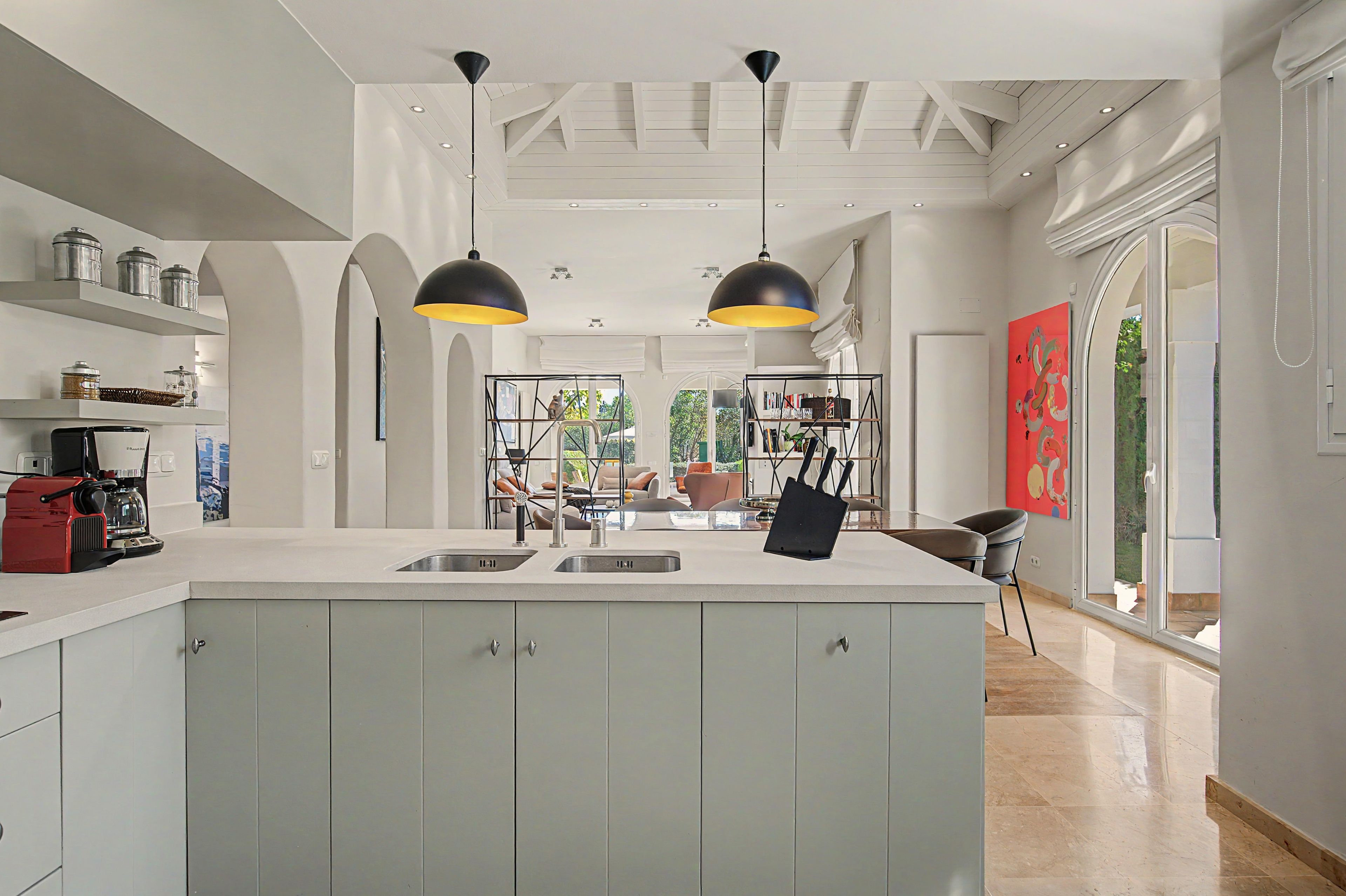 A modern kitchen with a central island, pendant lighting, and a view to the outdoors.