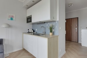 Una cocina moderna con armarios blancos, un microondas integrado y un lavamanos.