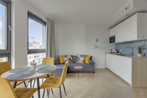 Un apartamento moderno con comedor, sofá, cocina y ventanas amplias.