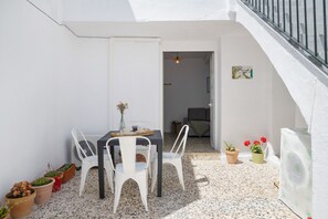 Eine kleine Terrasse mit Tisch und Stühlen, Blumentöpfen und einer Treppe.