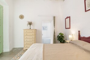 A bedroom with a bed, dresser, and a potted plant.