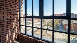 A room with a large window, brick walls, and a view of a cityscape. - Resi Apartments (Gdańsk)
