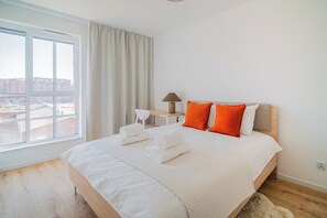 Une chambre d’hôtel avec un grand lit, un bureau, une lampe et une vue sur les bâtiments environnants.