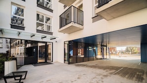 A modern building with glass doors, a covered outdoor area, and a courtyard with benches. - Resi Apartments (Gdańsk)