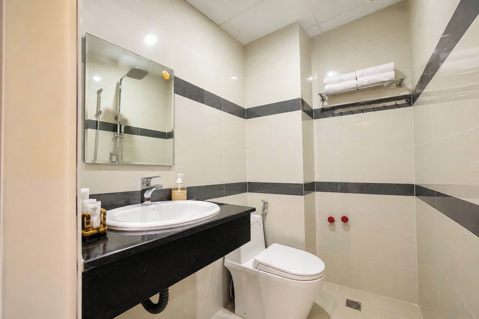 A bathroom with a sink, mirror, toilet, and shower.