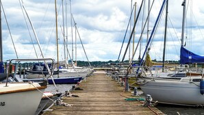 Un muelle de madera con varias embarcaciones amarradas en un puerto deportivo.