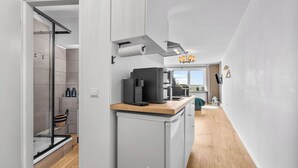 Cocina moderna con cafetera, horno empotrado y vistas al exterior.