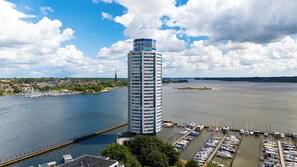 A tall building with a cylindrical shape, a marina with boats, and a river. - Wikingernest 13.10 - in the Viking Tower, Schlei View, Loggia (Schleswig)
