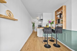 A modern kitchen with a wooden floor, white cabinets, and a dining area with black chairs. - Wikingernest 13.10 - in the Viking Tower, Schlei View, Loggia (Schleswig)