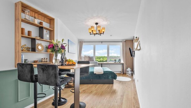 Una habitación moderna con comedor, cama, ventana con vistas y un candelabro.