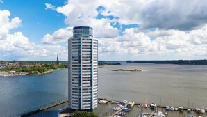 Un edificio alto con un puerto deportivo y barcos en primer plano.