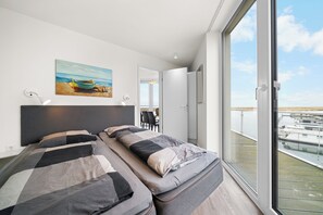 Et moderne soveværelse med en stor seng, et billede på væggen og en balkon med udsigt til både.