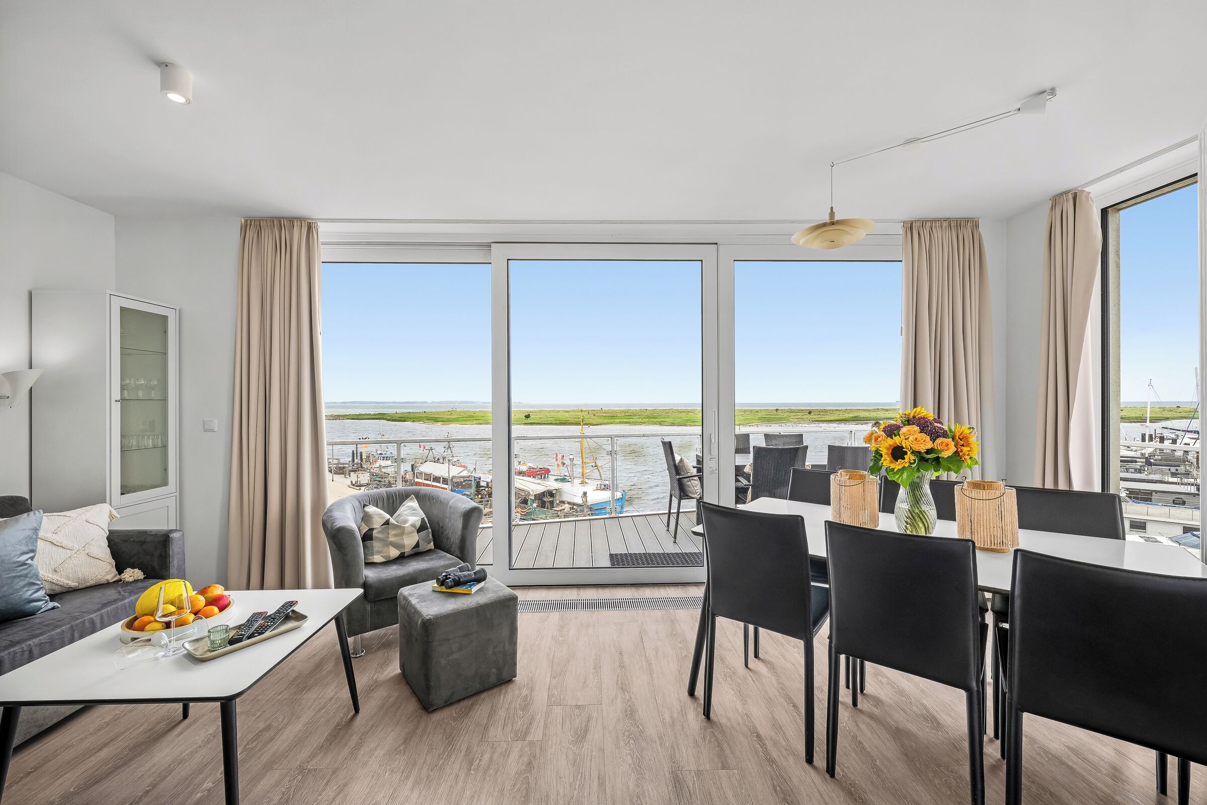 En moderne stue med spiseområde, store vinduer og havudsigt.