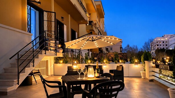 Eine Dachterrasse mit Esstisch, Stühlen, einem großen Sonnenschirm und einer Champagnerflasche.