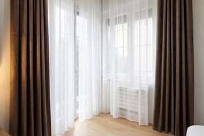 A room with a large window, a radiator, and brown curtains. - Elegantis Aventino Flat with Private Terrace | Colosseo & Circo Massimo (Roma)