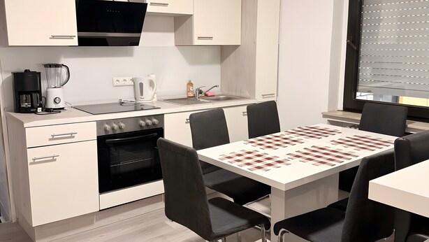 Une cuisine moderne équipée d’une cuisinière, d’un four et d’une machine à café, ainsi qu’un coin repas avec une table d’échecs.