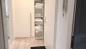 Un couloir avec un placard contenant des draps blancs soigneusement pliés.