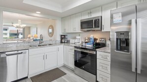 Una cucina moderna con mobili bianchi, elettrodomestici in acciaio inossidabile, forno integrato e dispenser d'acqua.