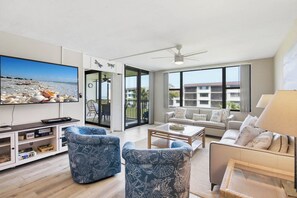 Ein modernes Wohnzimmer mit Fernseher, Sofas, einem Couchtisch und einem Balkon mit Blick.