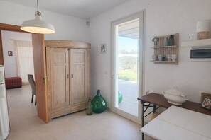 A kitchen with a wooden cabinet, a table, a hanging light, and a view through a glass door. - THE RED GELSO by Salento Sea Sky Travel Slow Live More (Nardo')