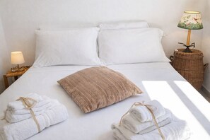 A neatly made bed with white linens and a brown pillow, a lamp on a side table, and a wicker basket. - THE RED GELSO by Salento Sea Sky Travel Slow Live More (Nardo')